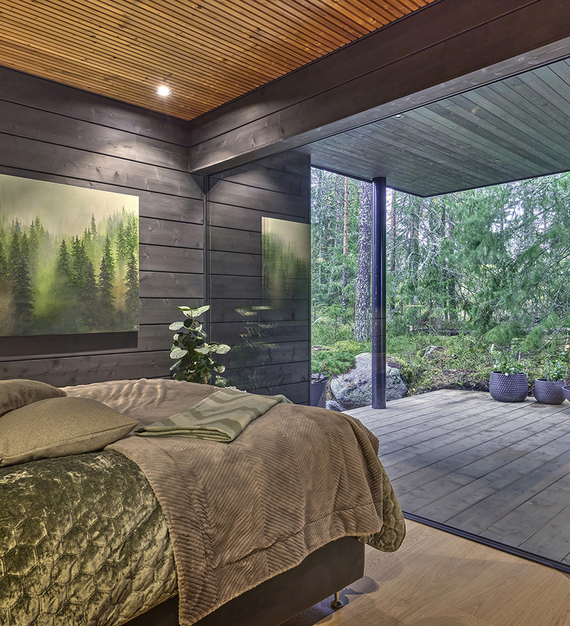 The large window in the log house bedroom reveals a calming forest view.